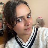 A circular profile picture of a young South Asian woman, Anushka Tyagi, smiling slightly in a white sweater with a plush bear toy on her shoulder.